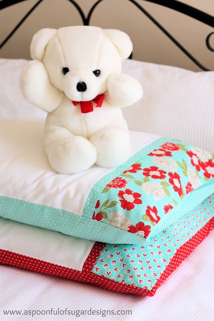 white teddy bear on top of 2 pillows