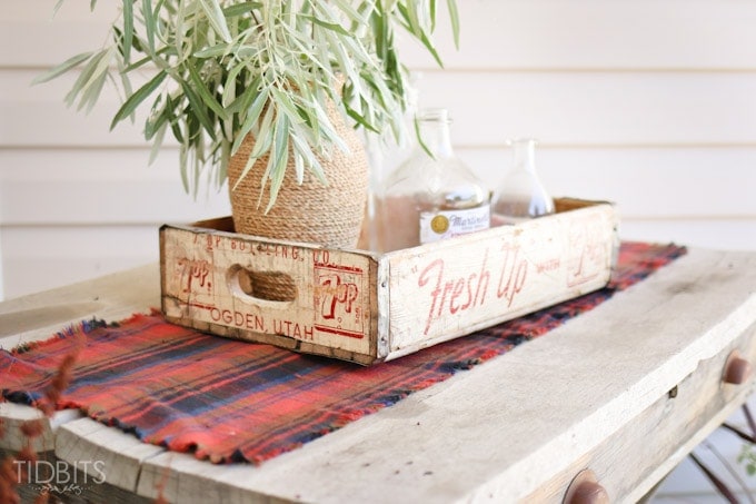 A DIY flannel table runner sits on a table with other fall front porch decor