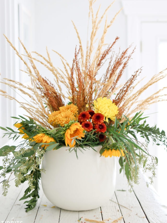 Spruce up your home decor with layered fall floral arrangement.  Fall floral arrangement sits on a white table.