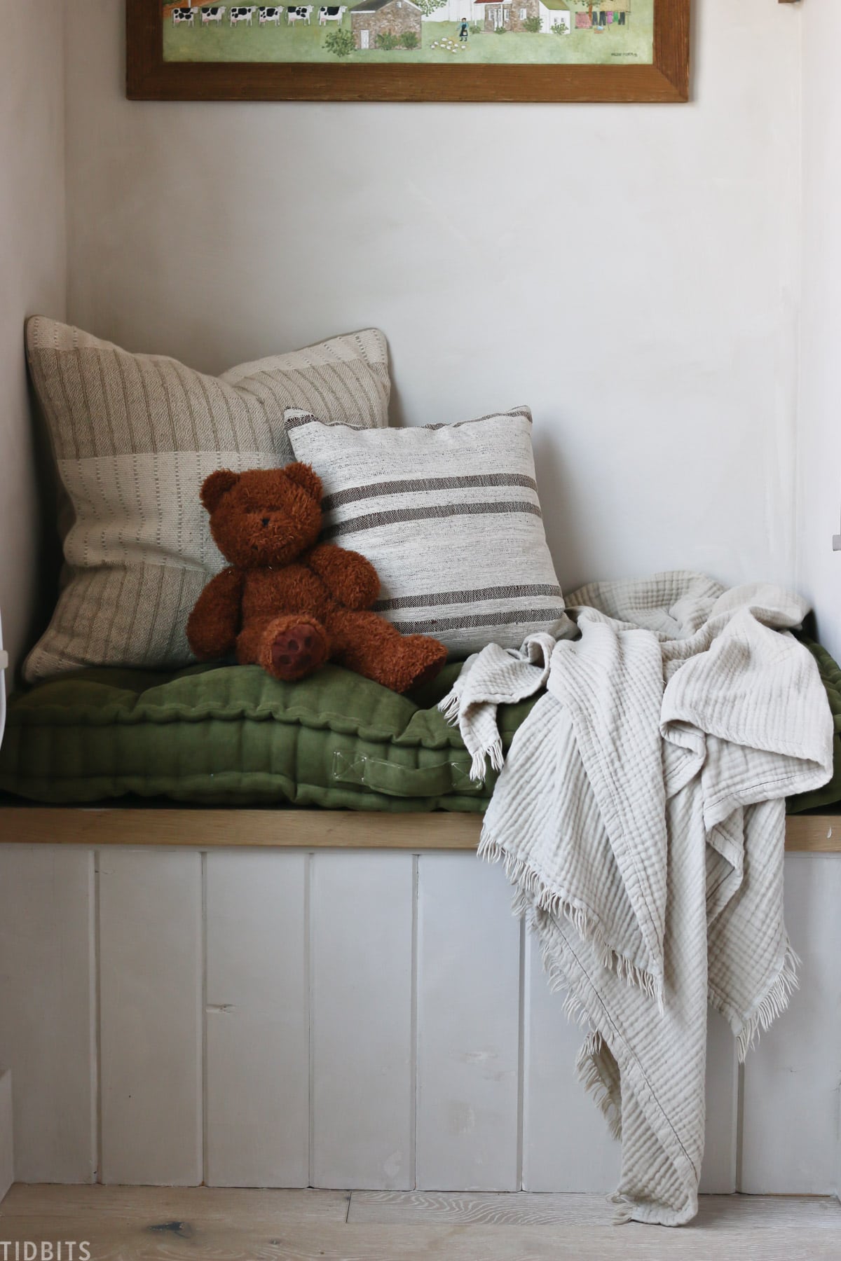 teddy bear, throw pillows, a throw blanket, and a cushion on top of a built in bench
