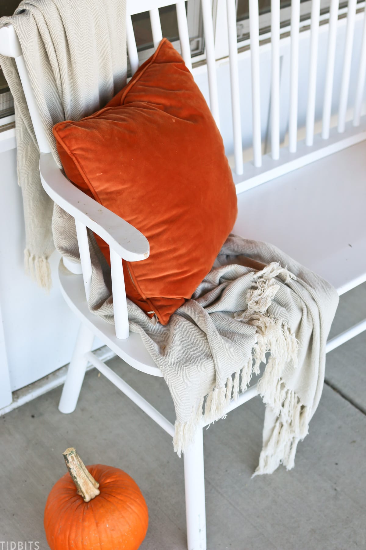 orange pillow and blanket placed on front porch bench