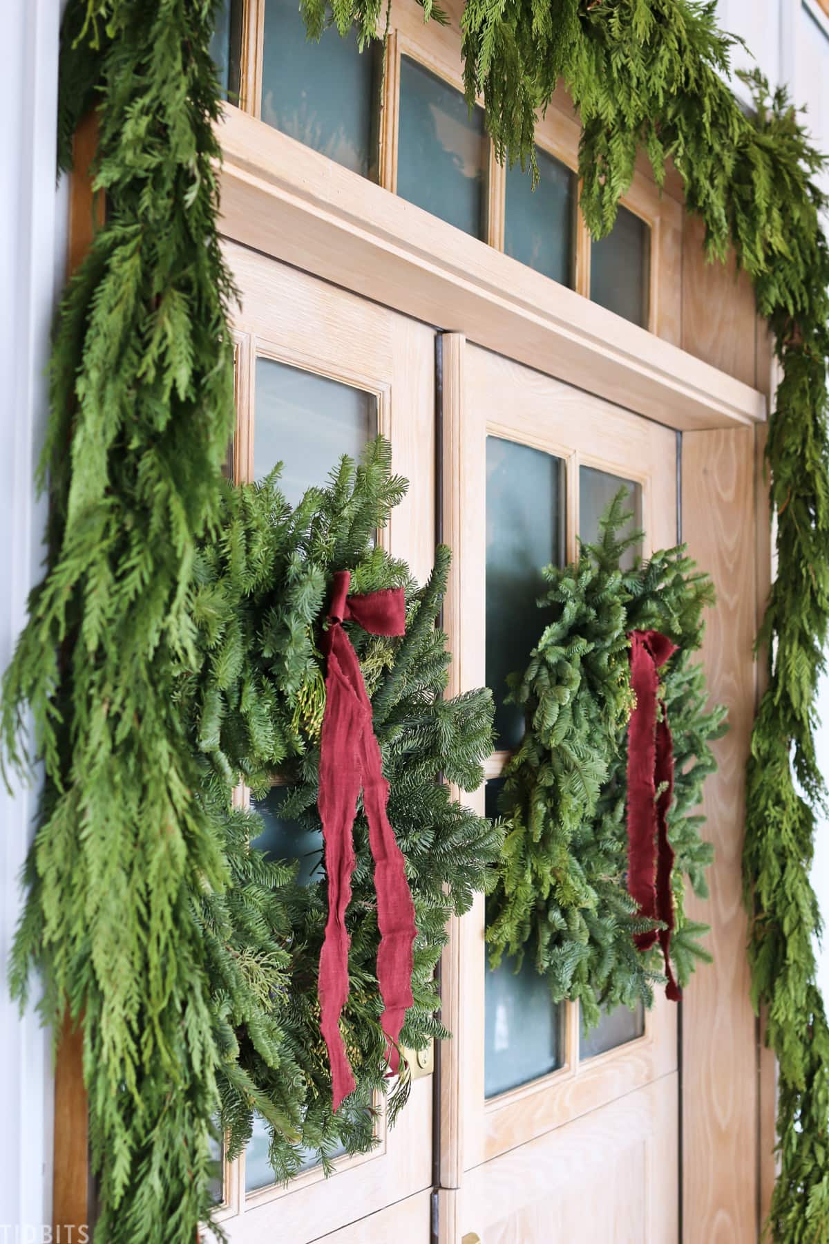 adding bows to fresh garlands on front doors