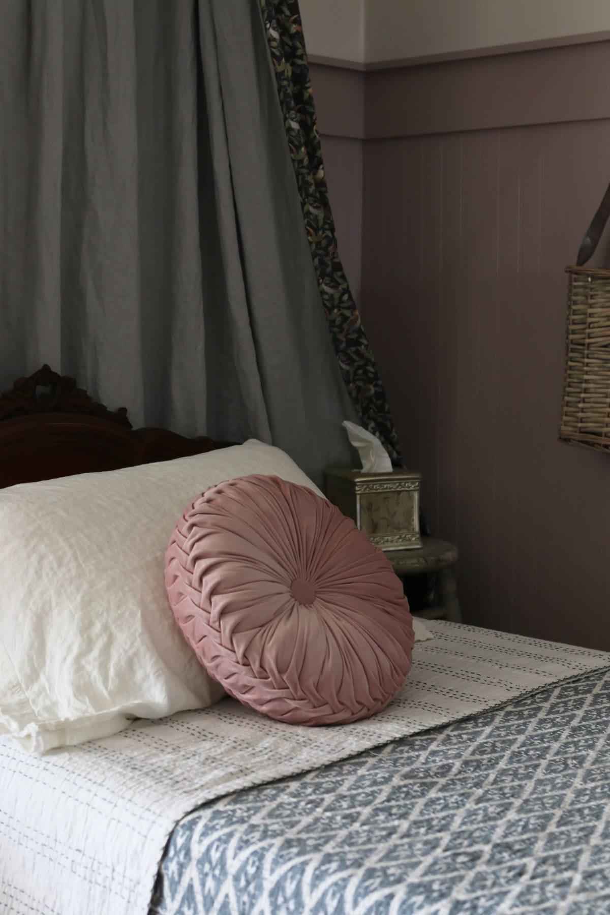 Pink round pillow on a cottage bed