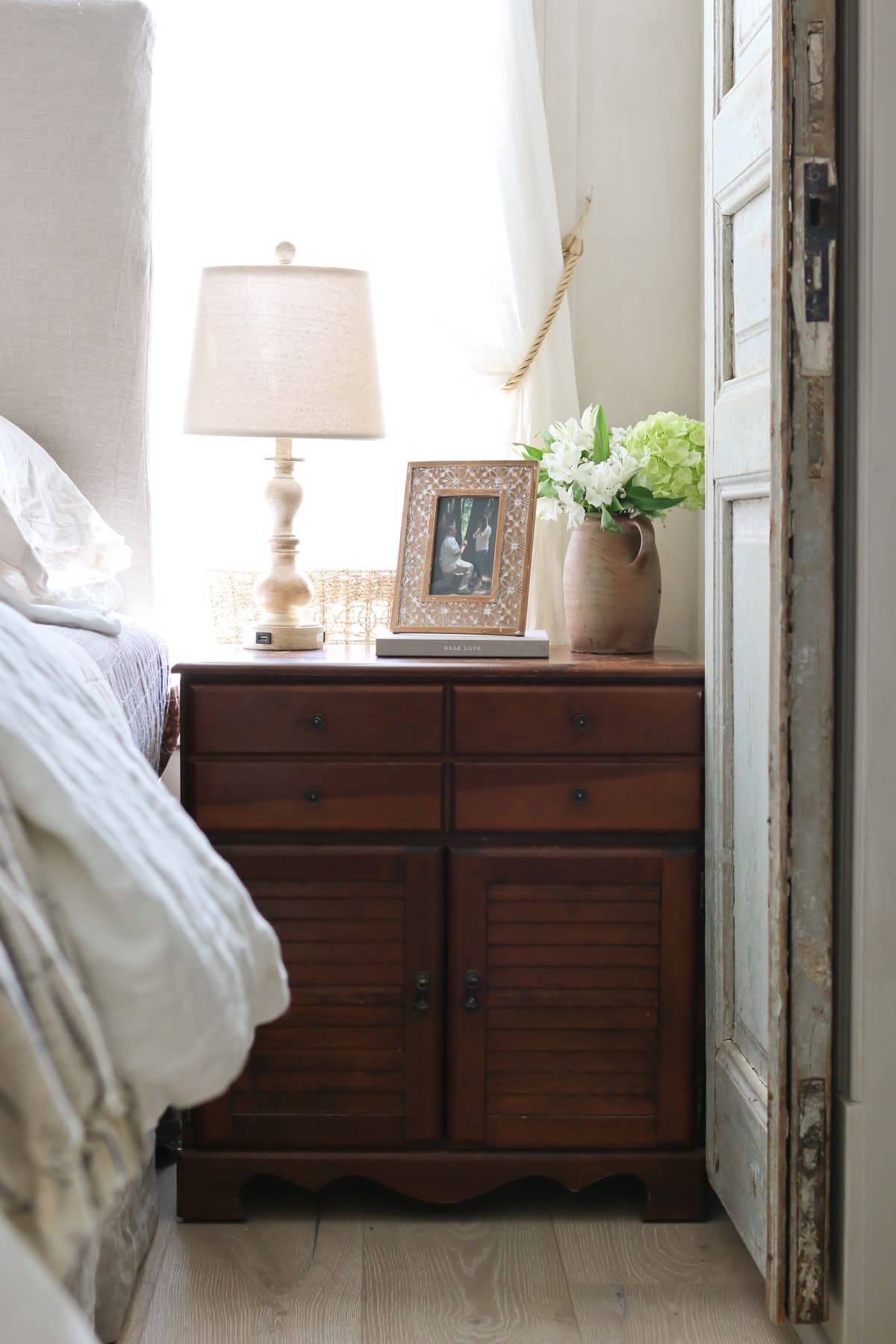 European farmhouse master bedroom with antique nightstand
