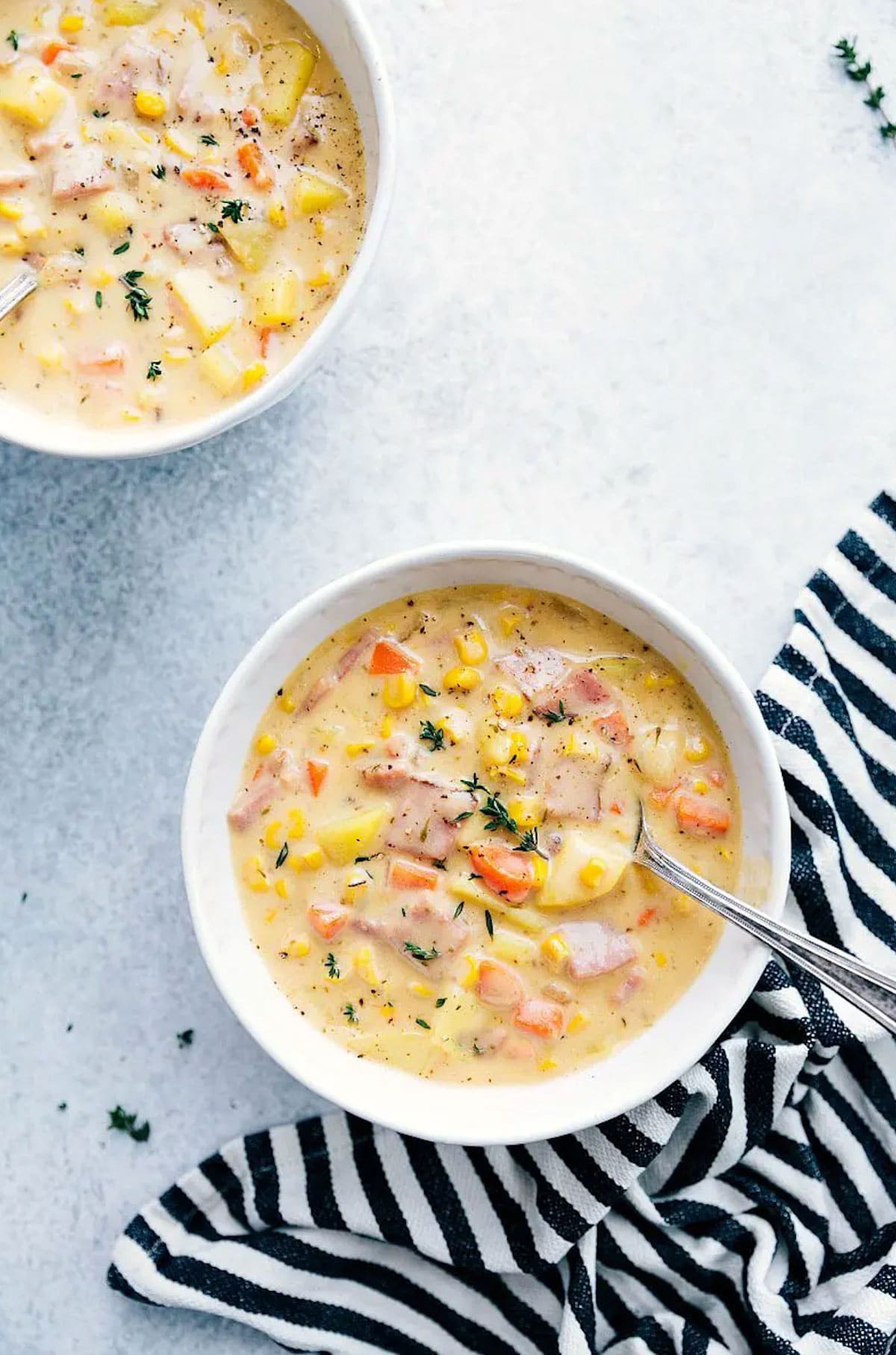Bowls of ham and potato soup with vegetables topped with sprinkle of herbs