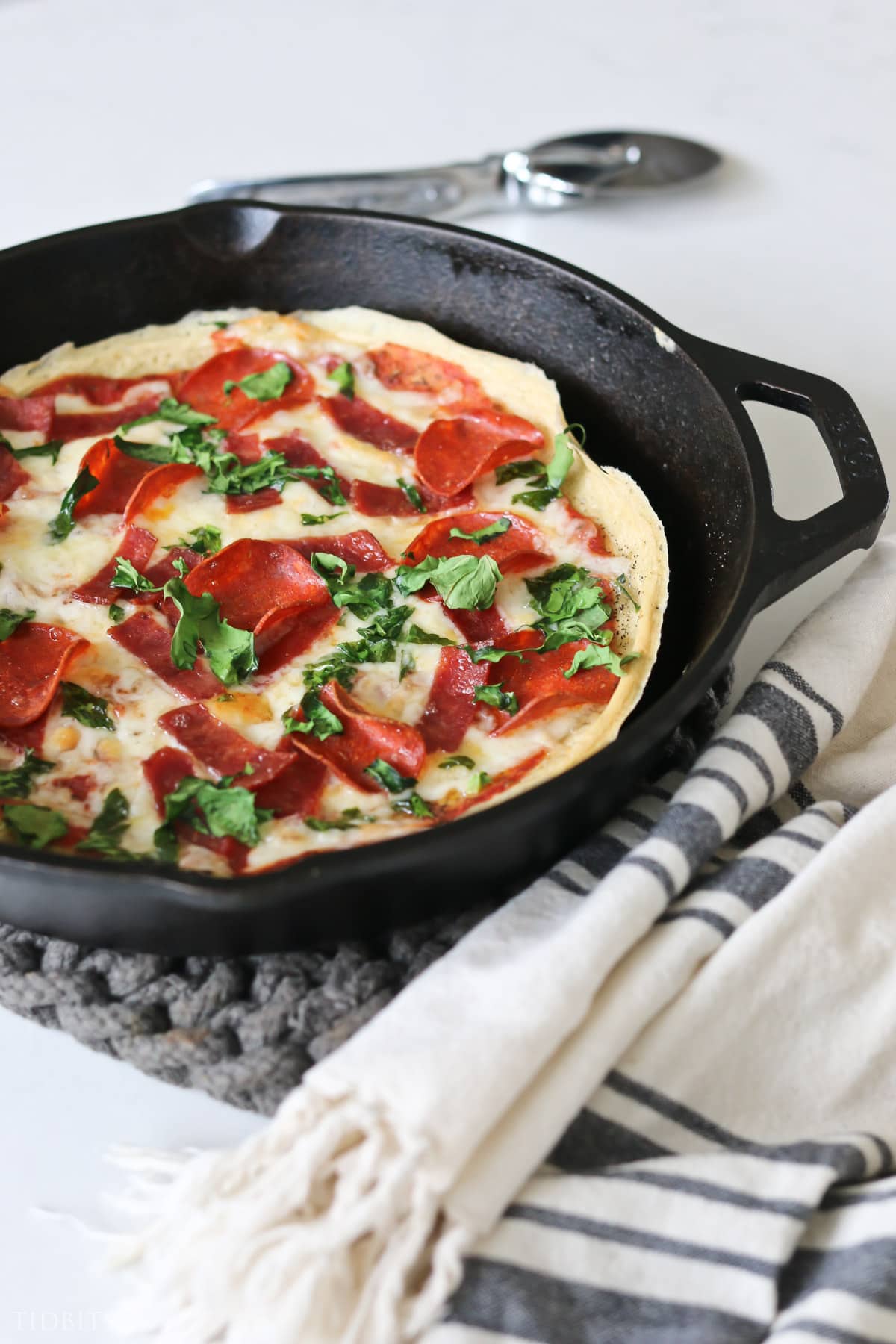 Sour dough pizza with pepperoni and herbs in a cast iron pan
