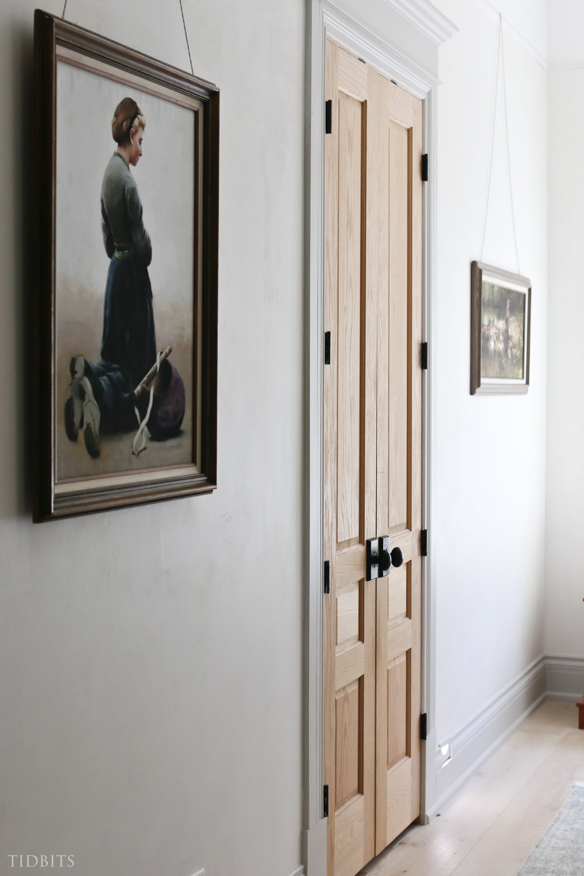 Tall white oak door next to large painting of woman kneeling