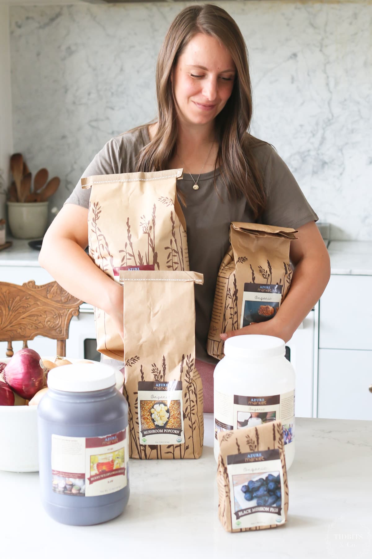 A woman holds an Azure Standard grocery haul in her kitchen