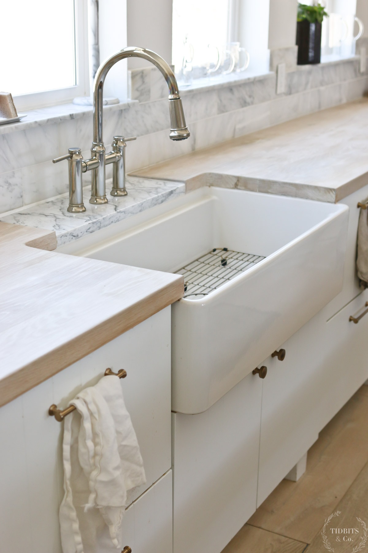 A white fire clay sink and a butcher block countertop with marble stone tap