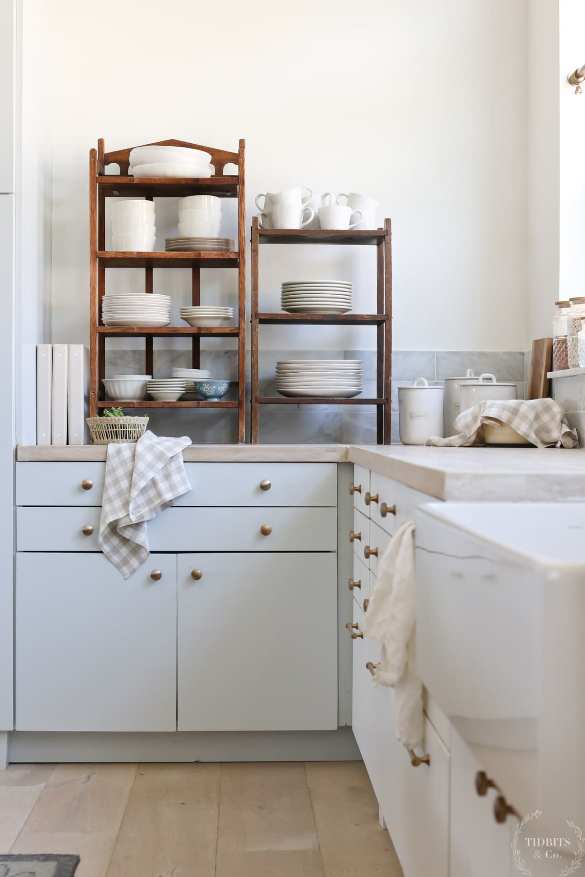 Wooden shelves with white dishes sit on a kitchen counter