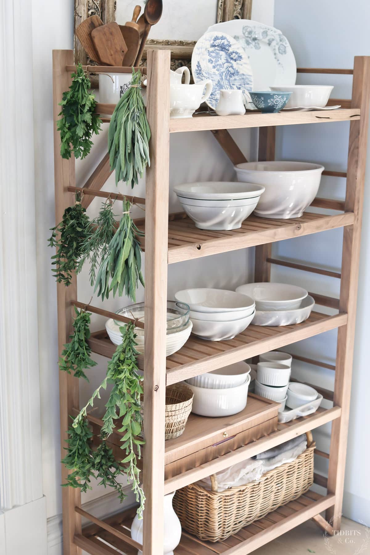 Bundles of herbs are tied to a wooden baker's rack
