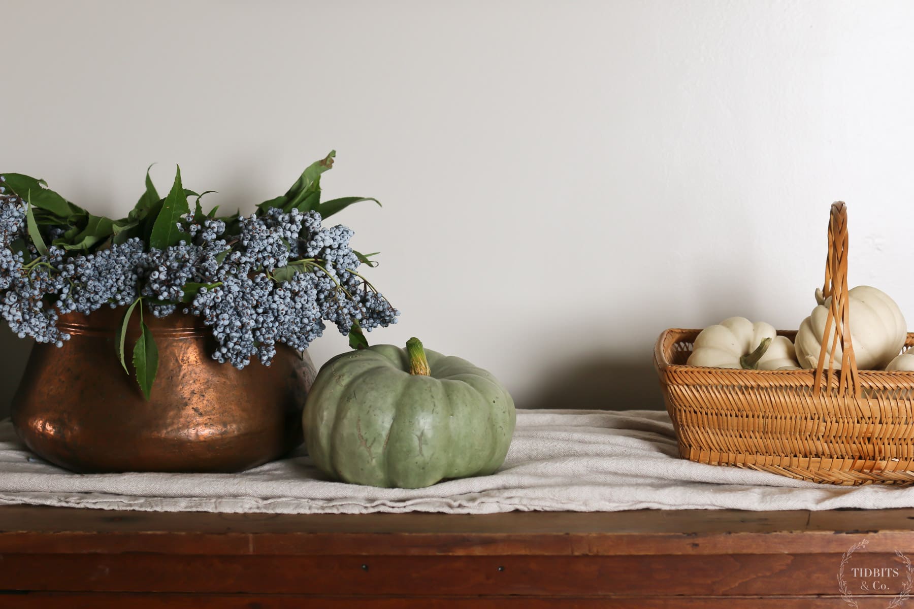 Berries and pumpkins used as fall decor sit on top of a dresser