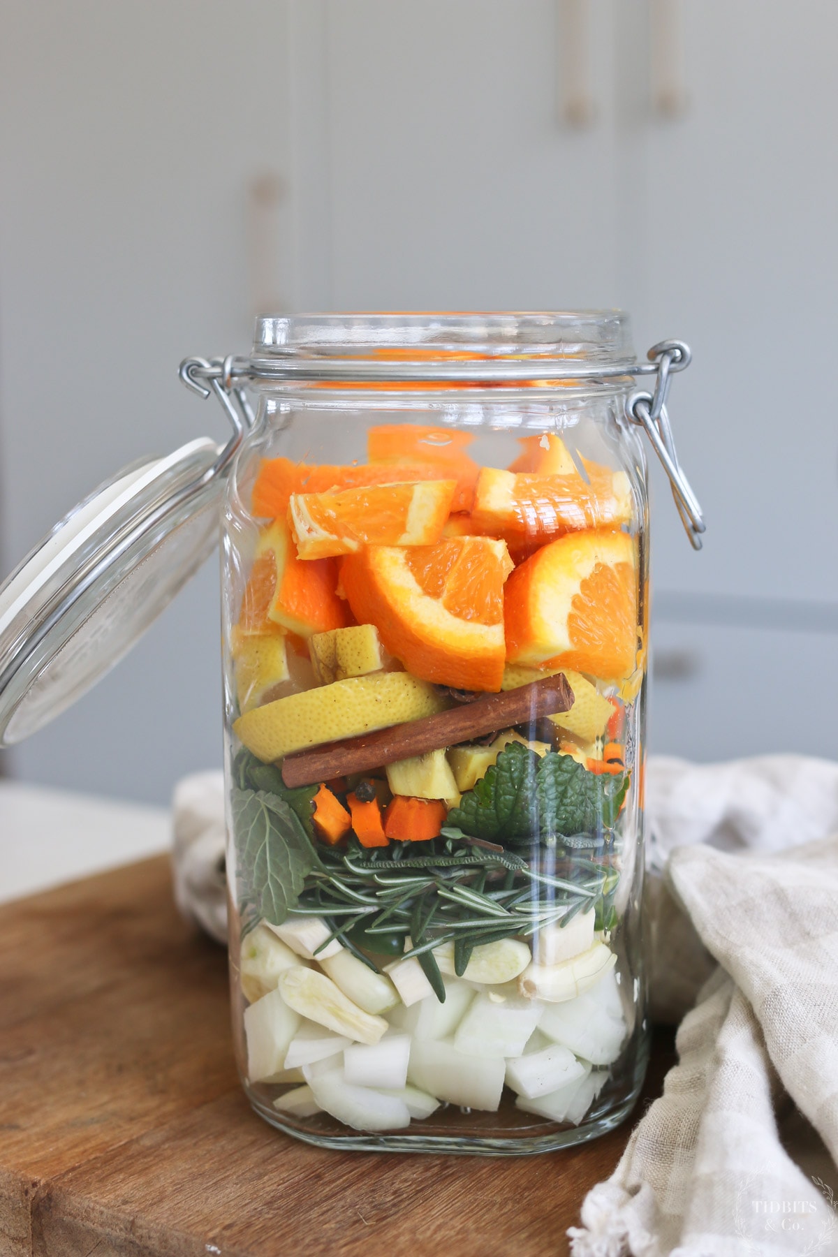 An open glass jar filled with layers of fruits, vegetables and herbs.