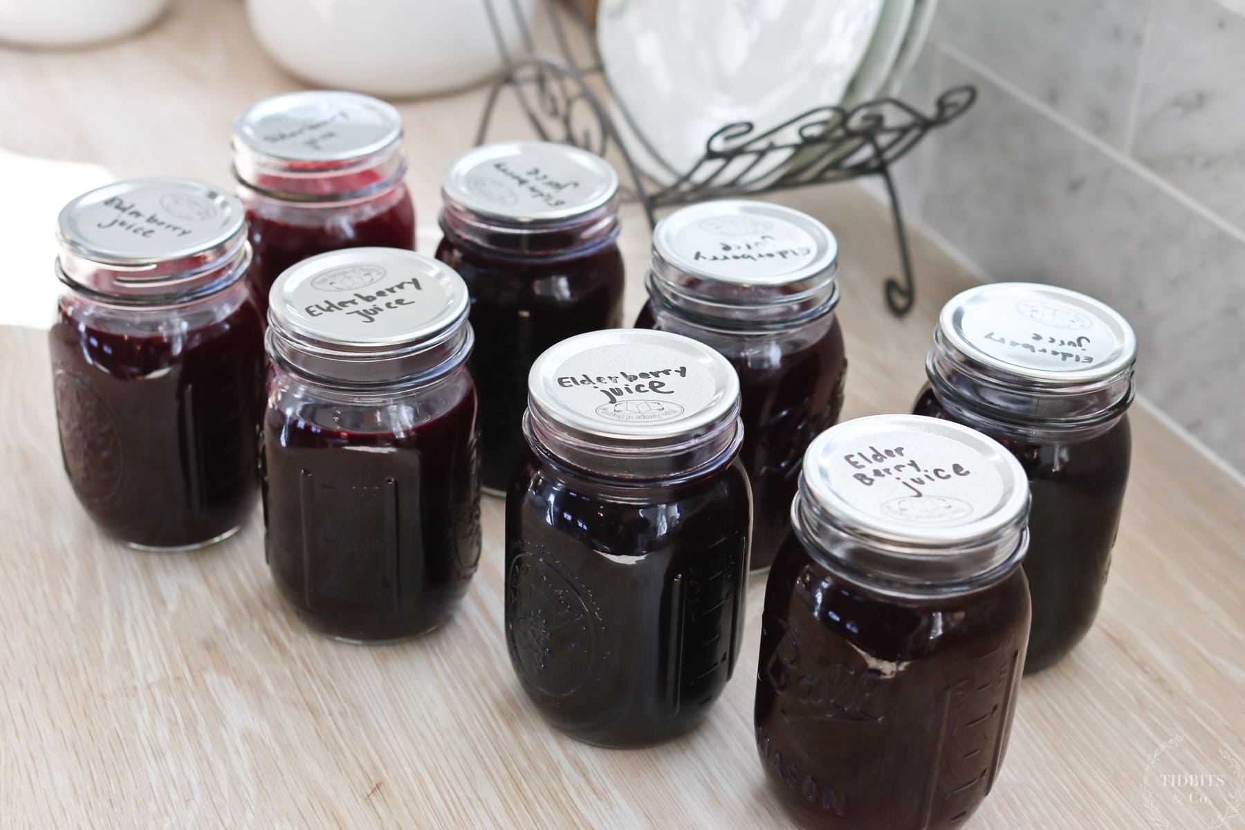 Jars of elderberry juice are lined up on a table
