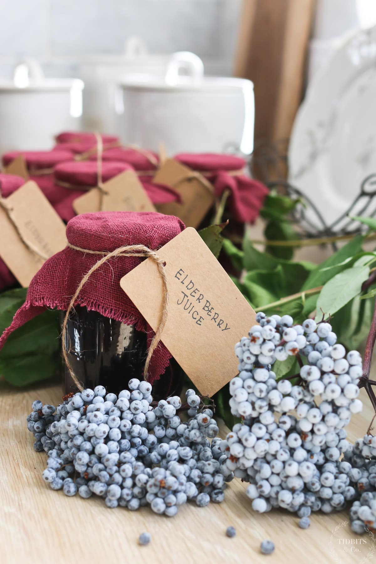 A bundle of fresh elderberries and bottles of elderberry juice with brown labels