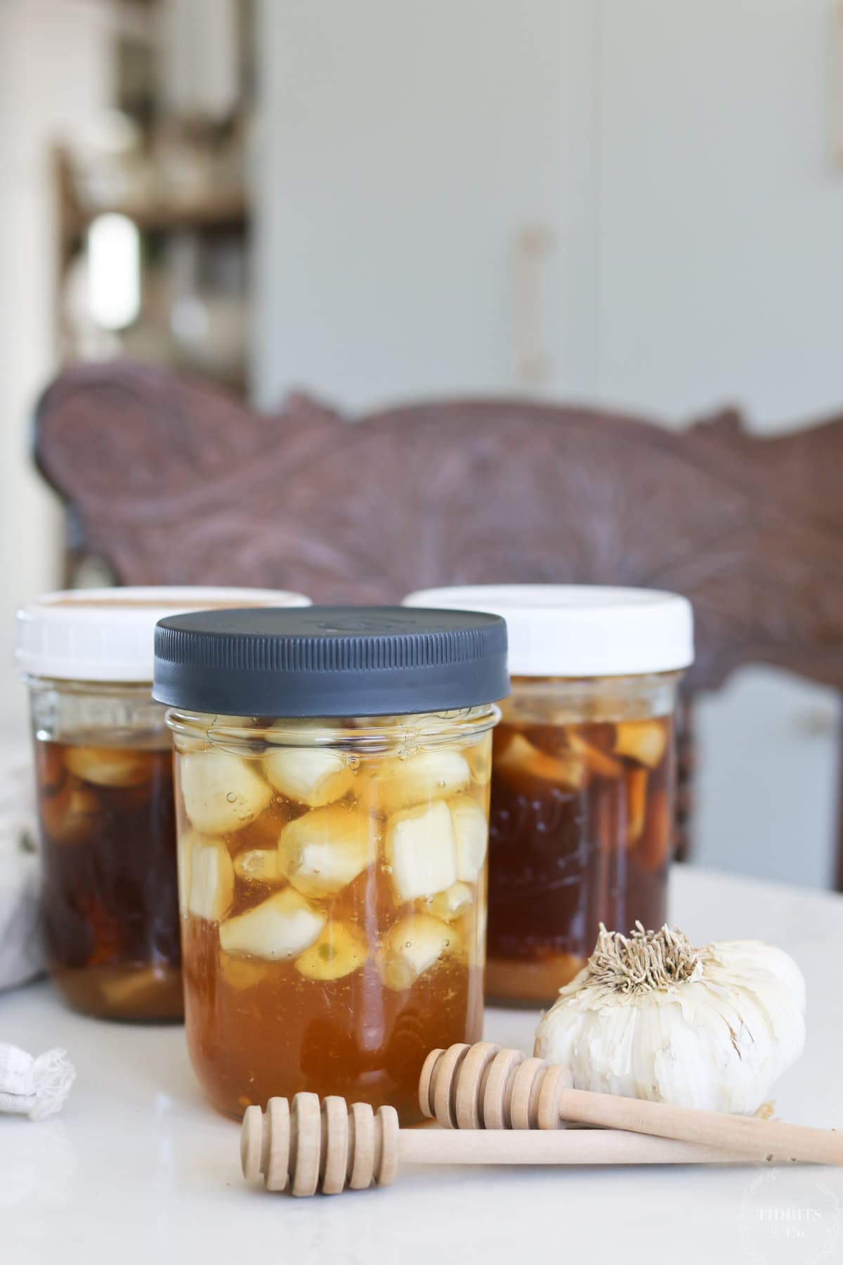 Three jars of fermented garlic infused honey sit on a table