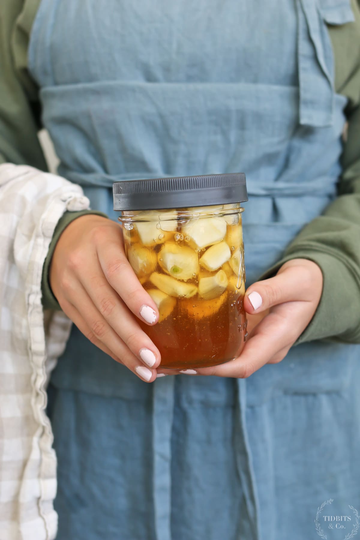 A girls holds a glass jar with immune-boosting garlic infused honey