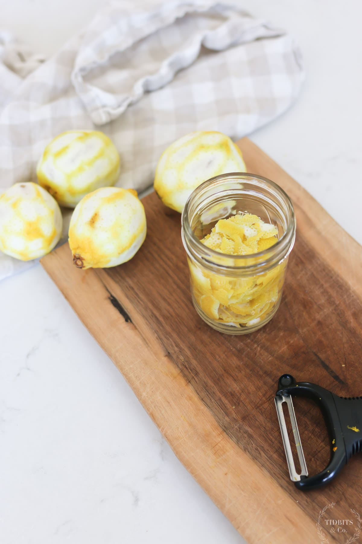 Peeled citrus fruit sits next to a mason jar full of peelings