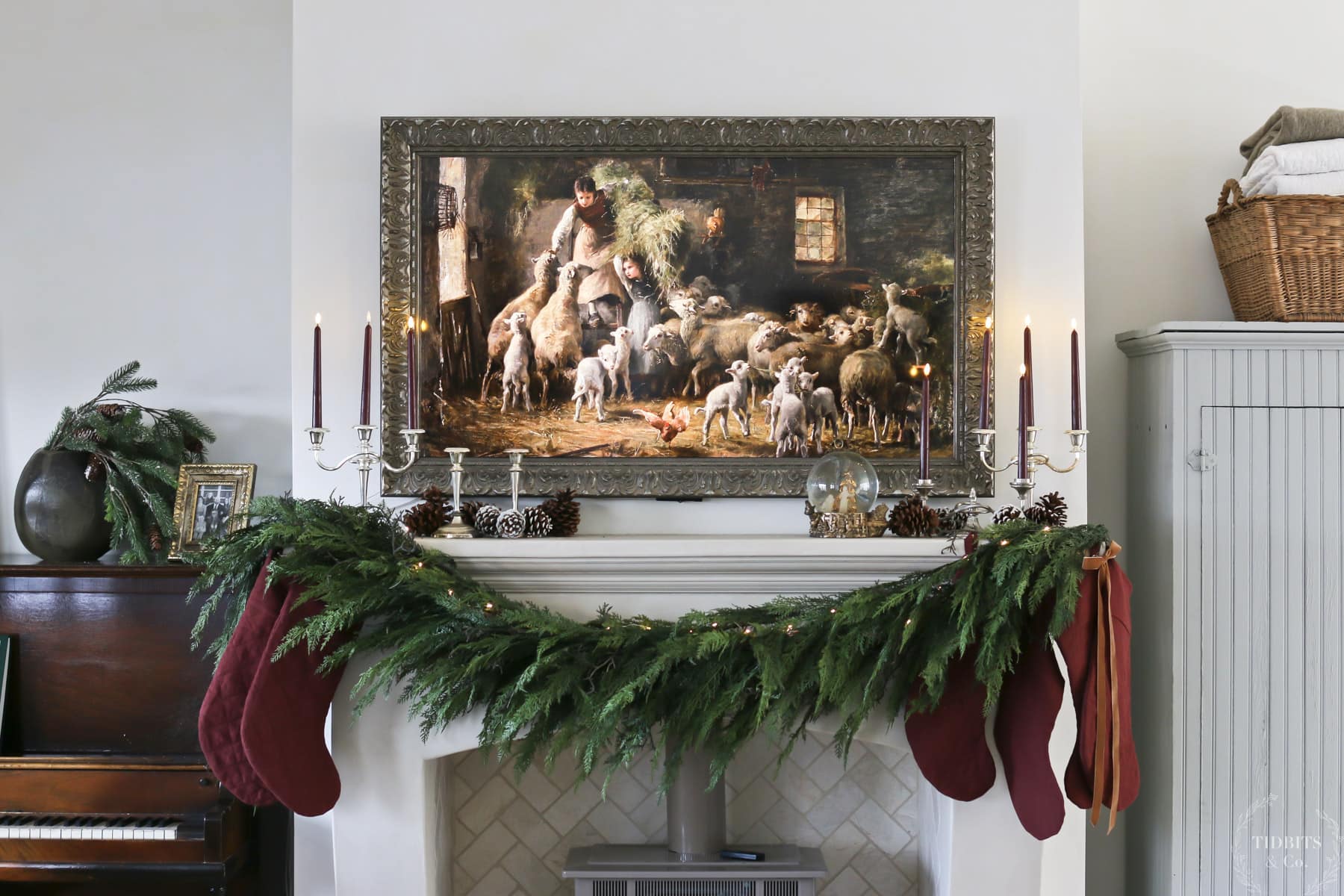 A Christmas fireplace with decorations and art hung above it