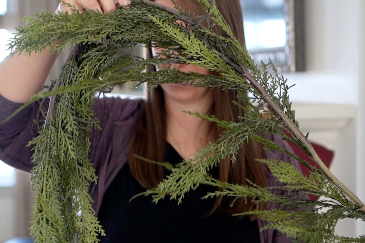 A woman holds a piece of artificial greenery