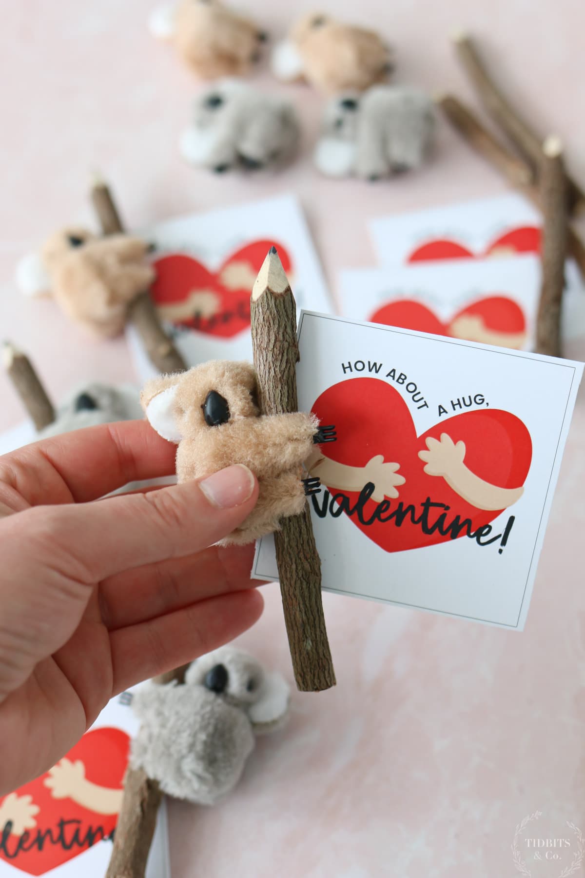  A person holds a valentine cards with a pencil and a small koala bear
