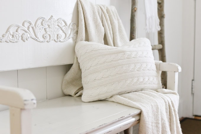 White bench with blanket and a DIY sweater pillow