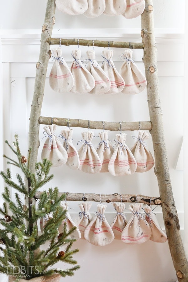 Christmas Countdown grain sack bags hanging on a log ladder. Pattern and tutorial available - by TIDBITS.