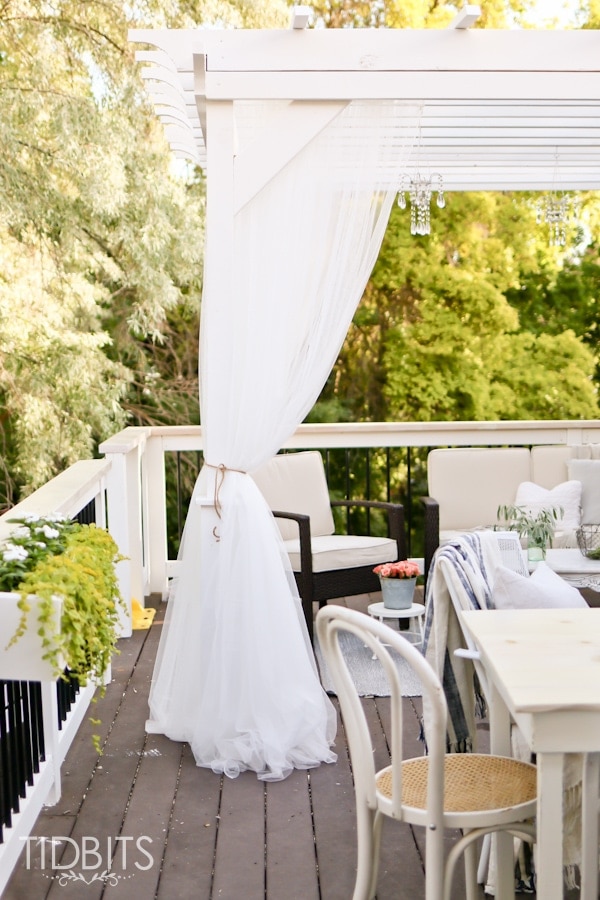 Curtained pergola on a deck for a beautiful and cozy retreat.  Deck makeover by TIDBITS.