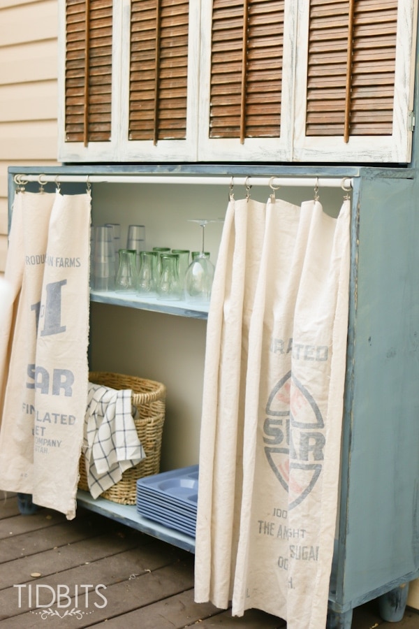 Vintage grain sacks used as curtains to conceal outdoor storage.  Deck makeover by TIDBITS.
