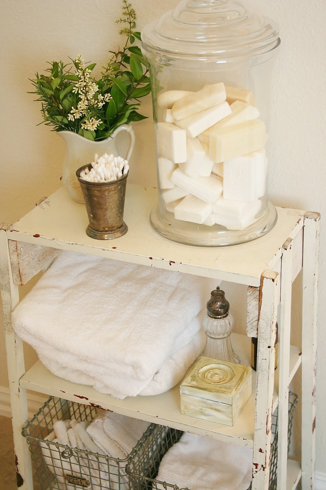 A glass jar holding bars of soap sits on a wooden shelf