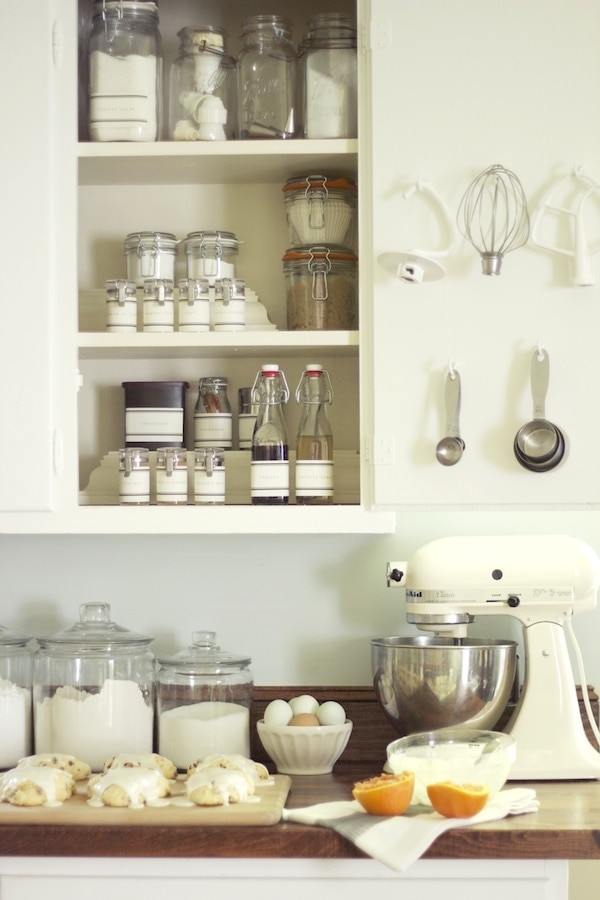 A beautifully organized cabinet holds glass jars of spices and baking ingredients