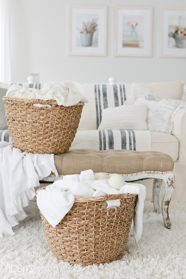 wooden laundry baskets on top of living room sofa with white sheets inside