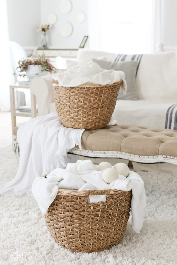 wooden laundry basket with white towels on top of living room sofa