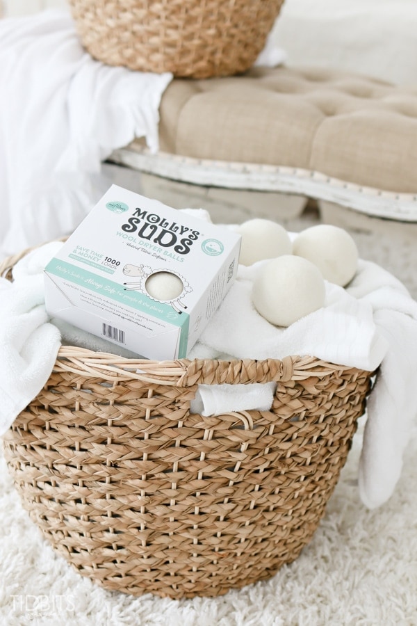 molly suds wool dryer balls on top of wooden laundry basket and white towels