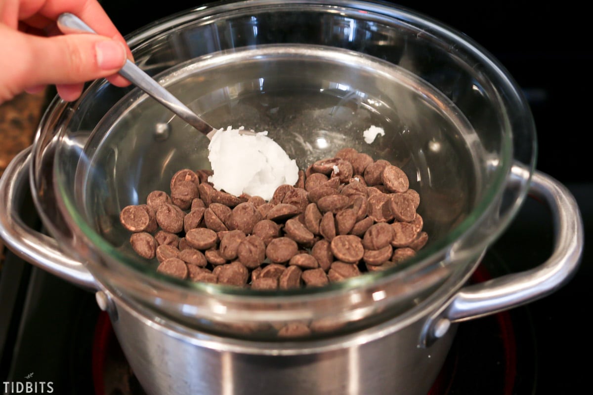 dark chocolate chips placed in a glass bowl above a pot to help them melt