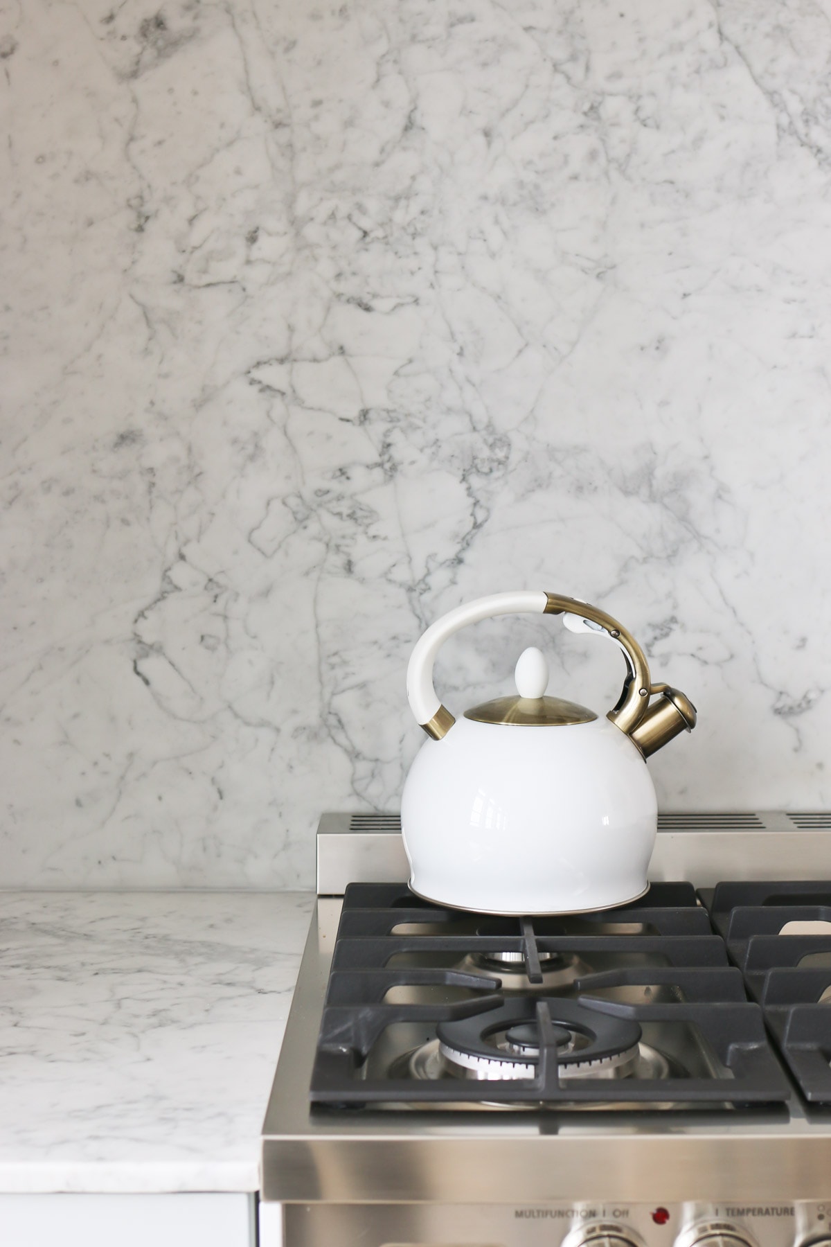 white kettle with gold accents on top of verona stove