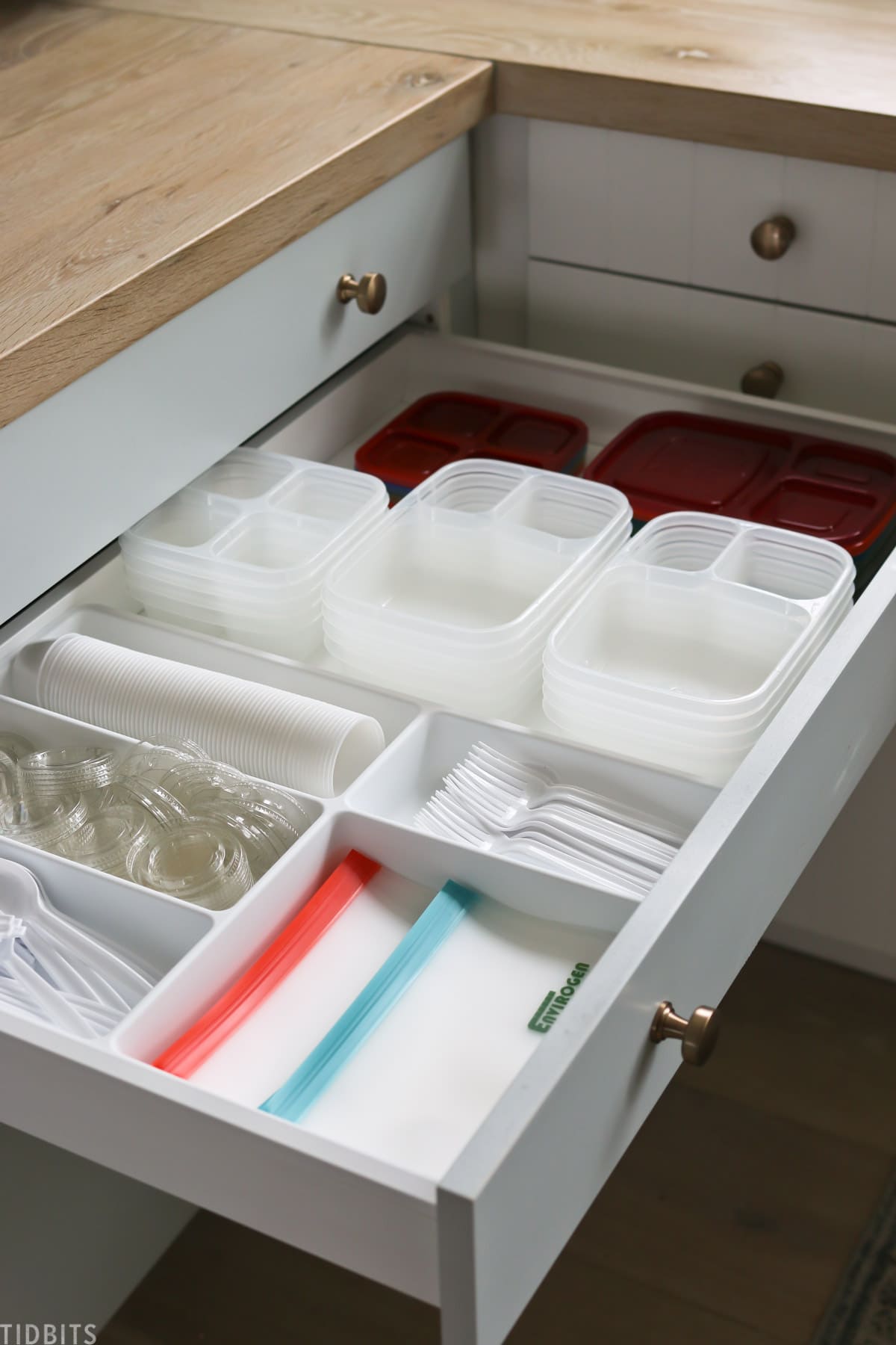 plaster containers, lids, plastic silverware, ziplock bags, and small containers organized in a kitchen drawer