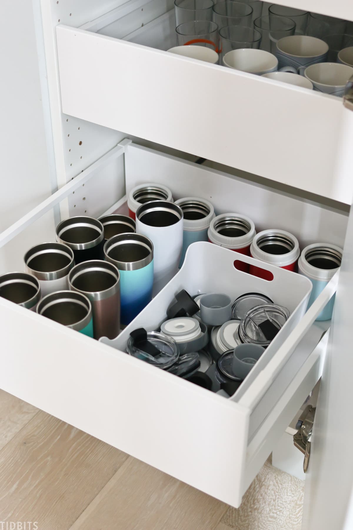 tumblers and matching lids organized in a kitchen drawer