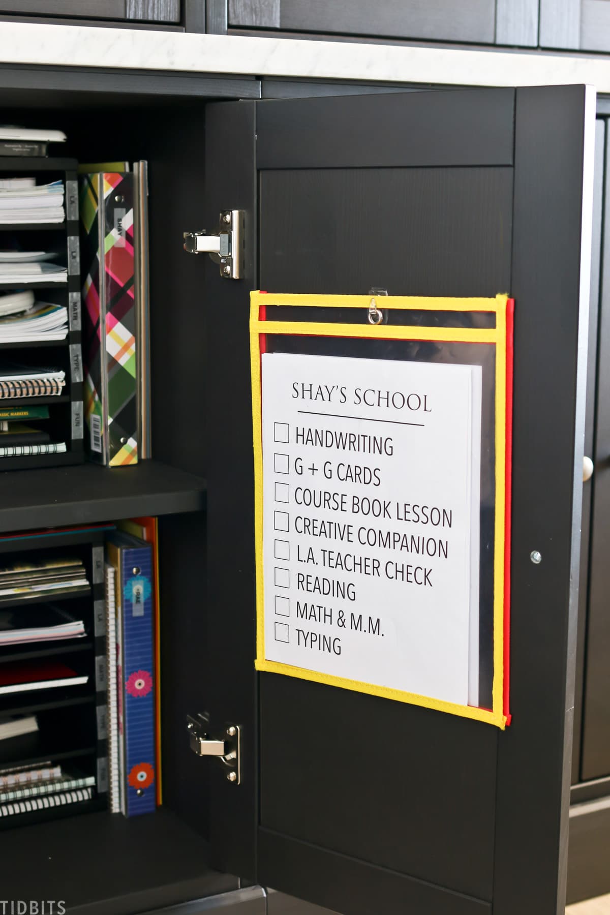 printed checklist hanging on the inside of a cupboard for homeschooling