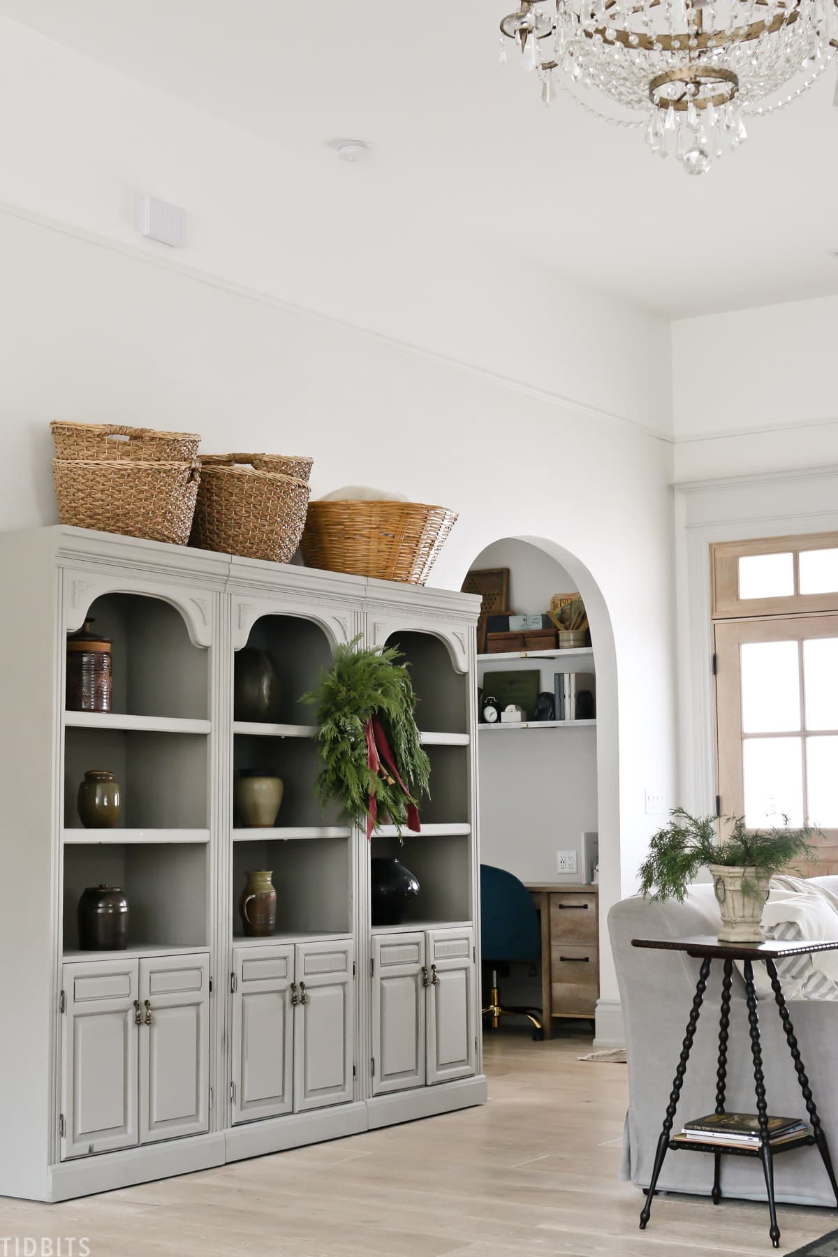 refurbished bookshelves with baskets and vases and wreath hanging from center bookshelf