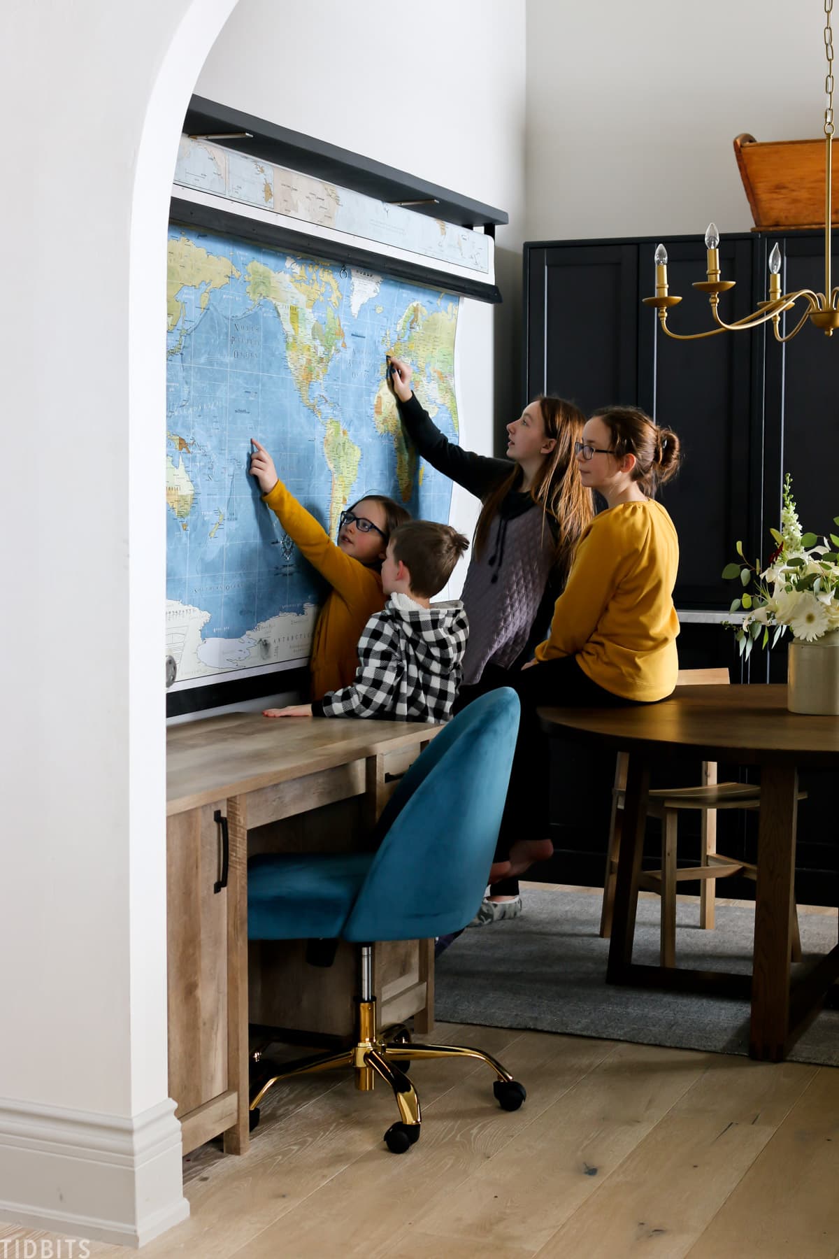 four kids looking at a world map in a converted room used for homeschooling