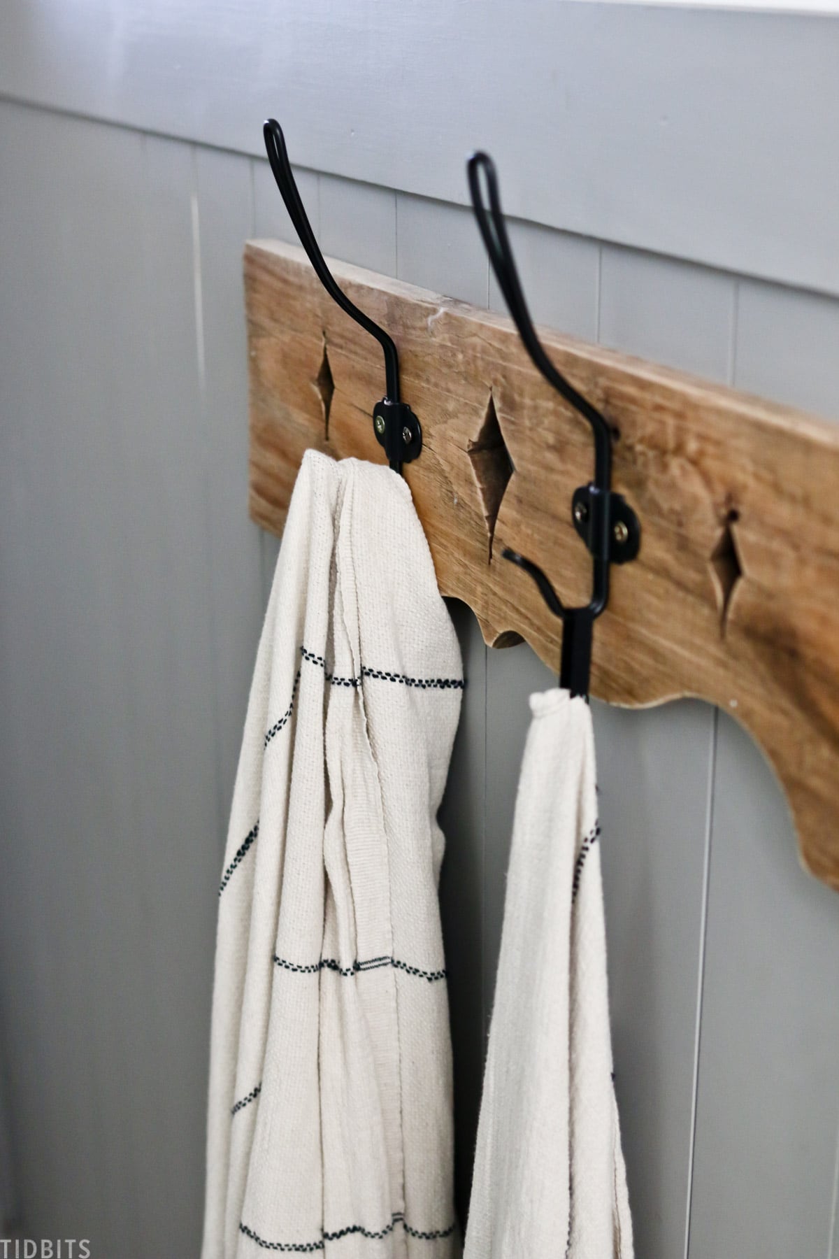 wooden towel rack with metal hooks hanging in split bathroom