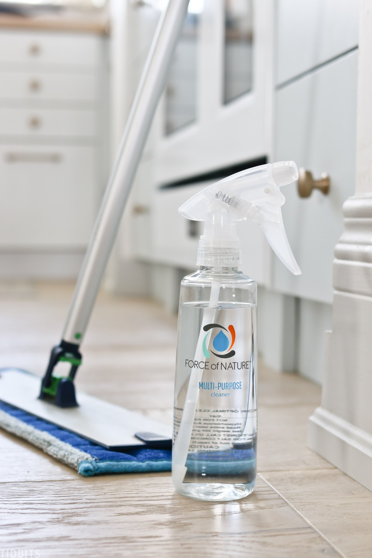 Force of Nature spray bottle that's filled with disinfectant spray and placed next to mop