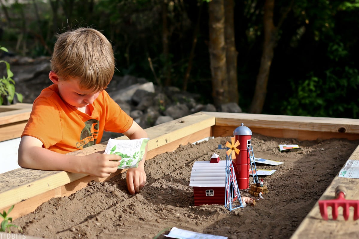 young boy planting in the raised garden bed