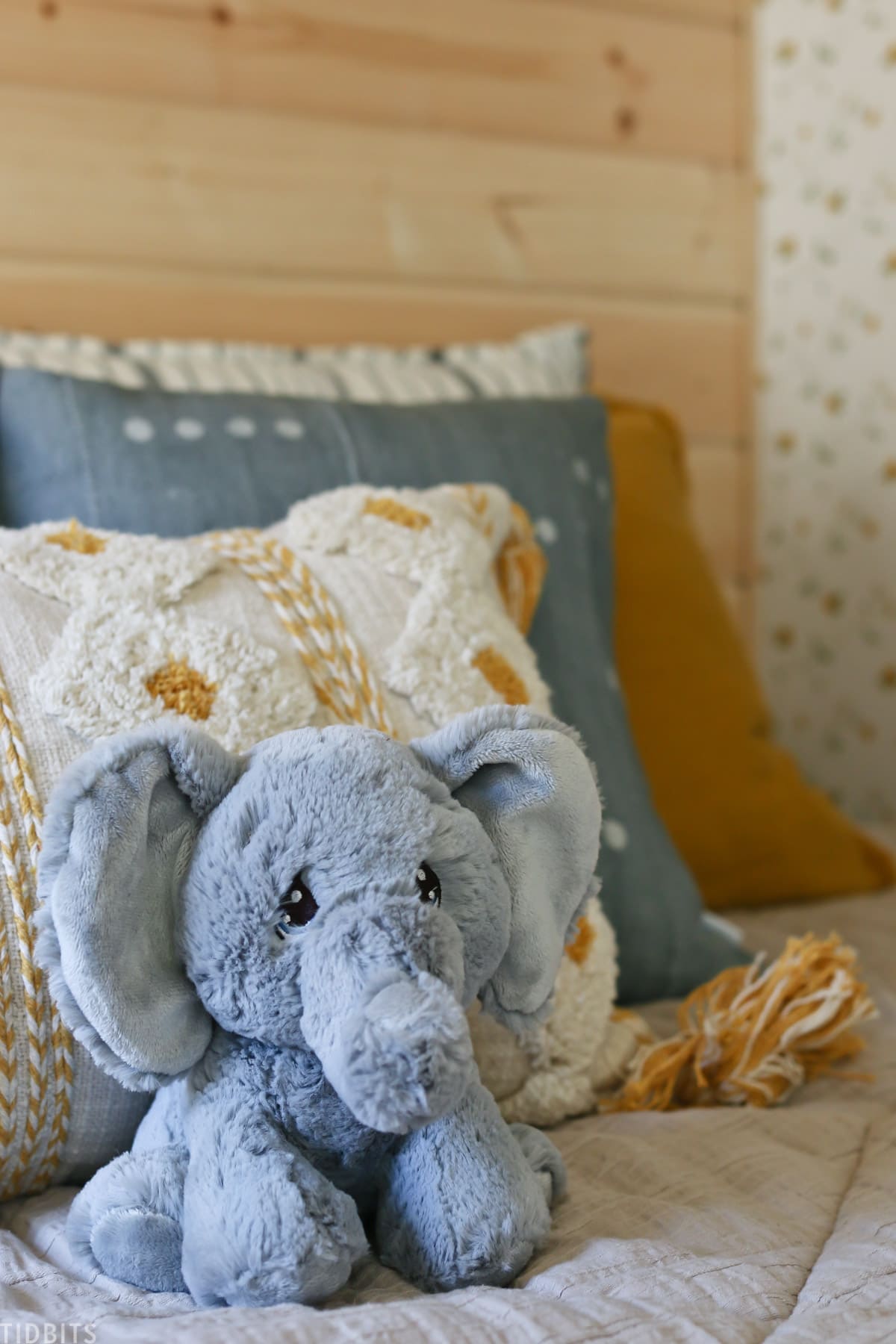 layered kids bed with throw pillows and stuffed elephant