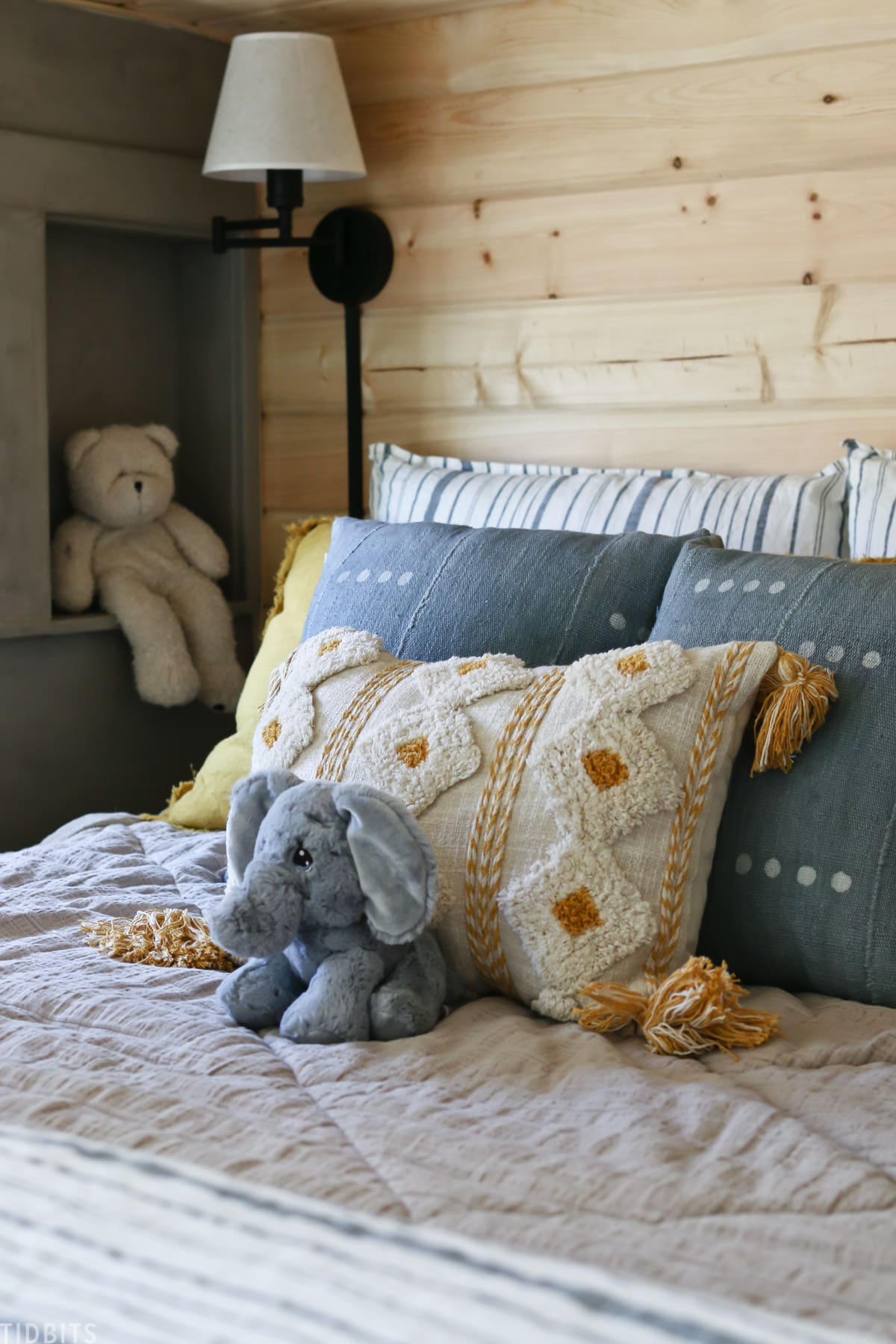 layered kids bed with throw pillows and stuffed elephant