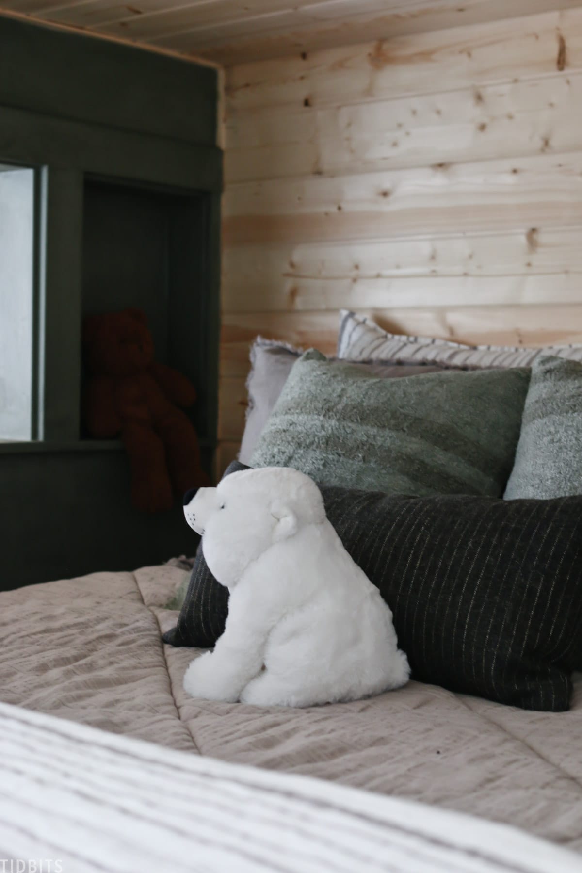 kids bed layered with linens, throw pillows, and a stuffed polar bear