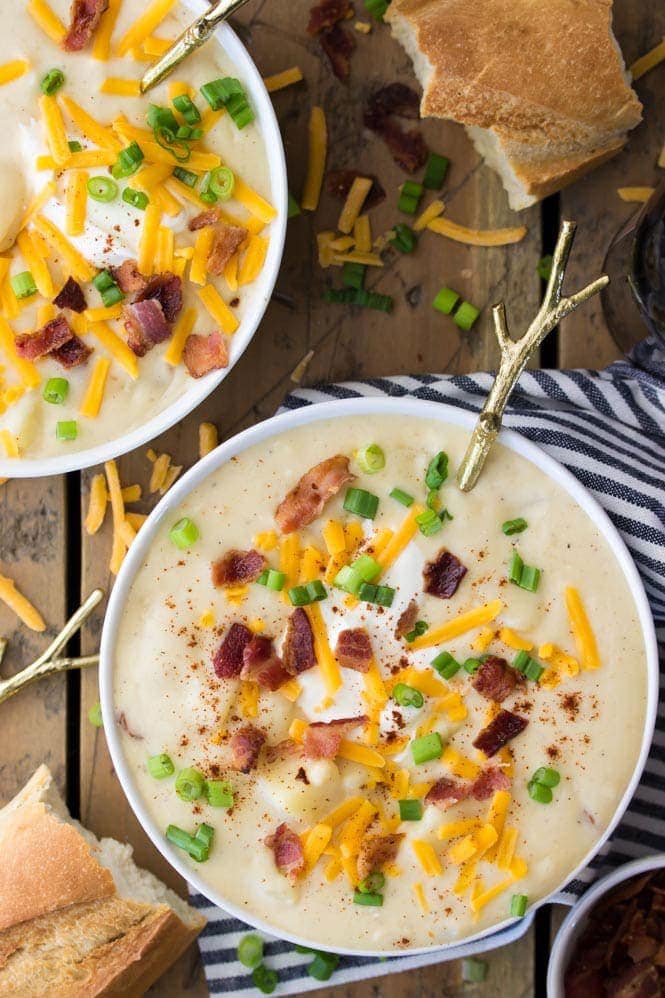 Creamy potato soup bowl topped with cheese, bacon, green onions and sour cream