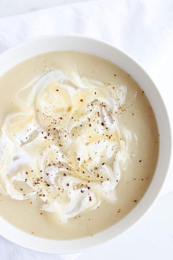 Bowl of instant pot potato soup with sour cream and a sprinkle of pepper