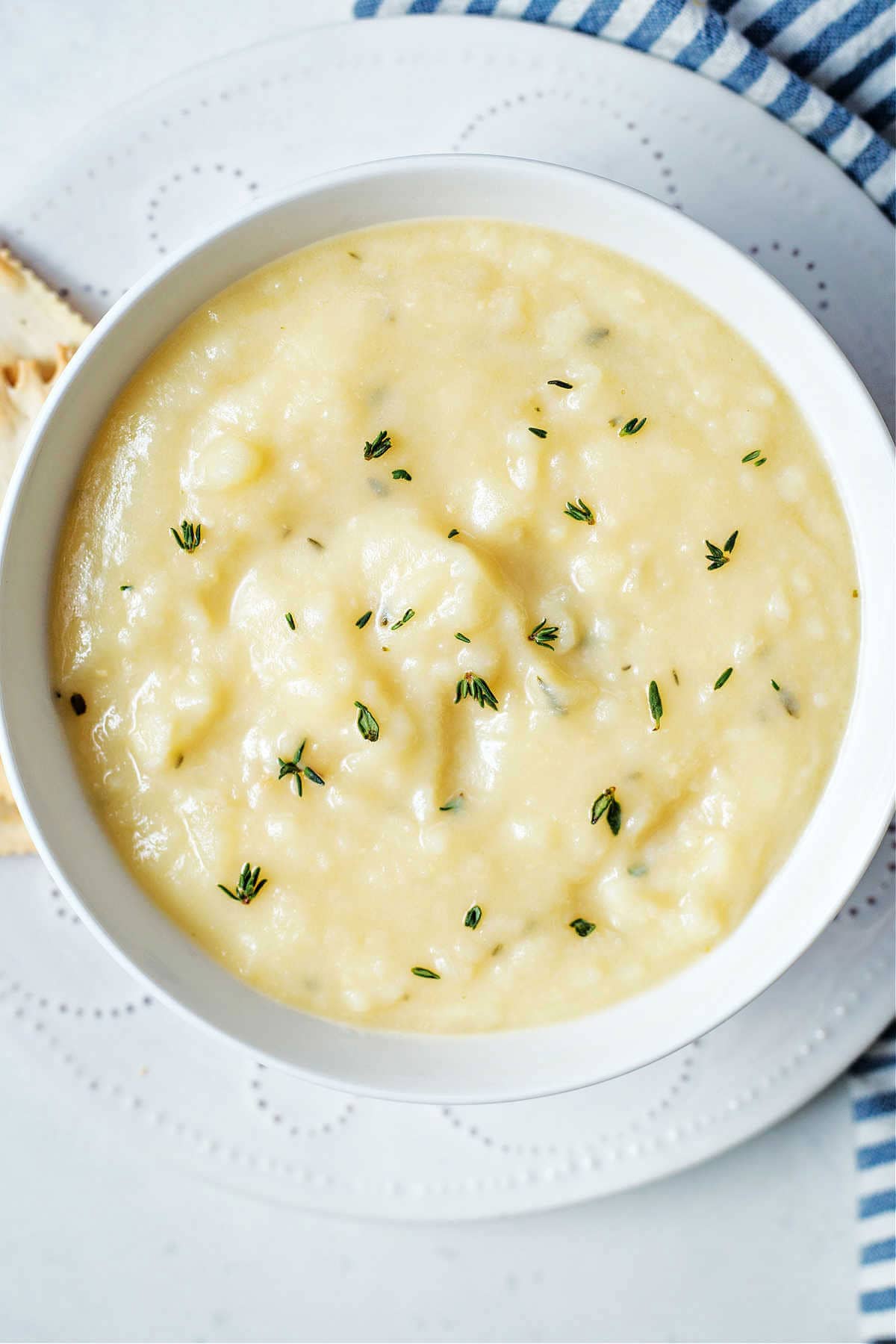 A bowl of creamy potato soup with herb garnish